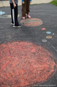 EPIC solar system project for kids that is easy to make by drawing the milk way galaxy, sun, planets, moon, asteroid belt and more with chalk on the driveway. Cute game idea for memorization too!